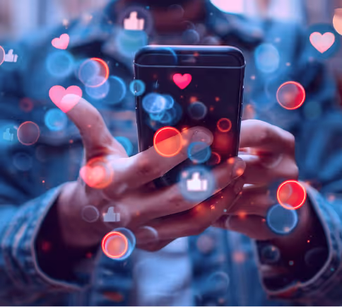 Close-up of hands holding a phone with floating heart and like icons representing social engagement.