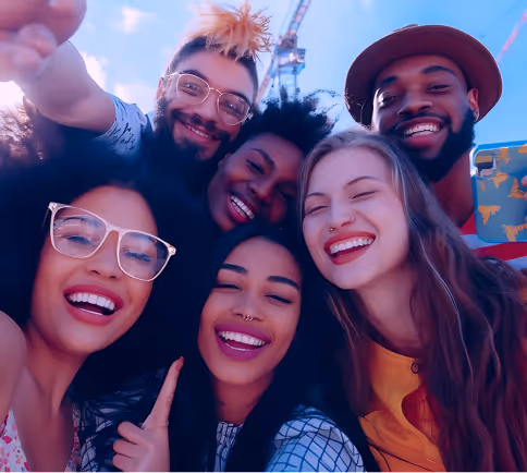 Group of smiling young adults taking a selfie outdoors on a sunny day, appearing joyful and close together.