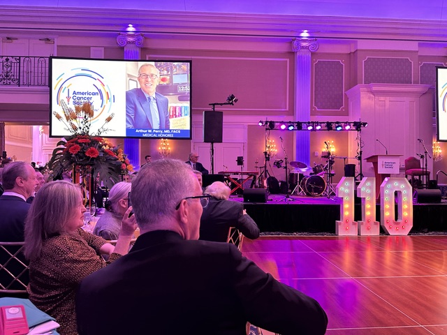 Evening event venue with stage lighting and a presentation screen