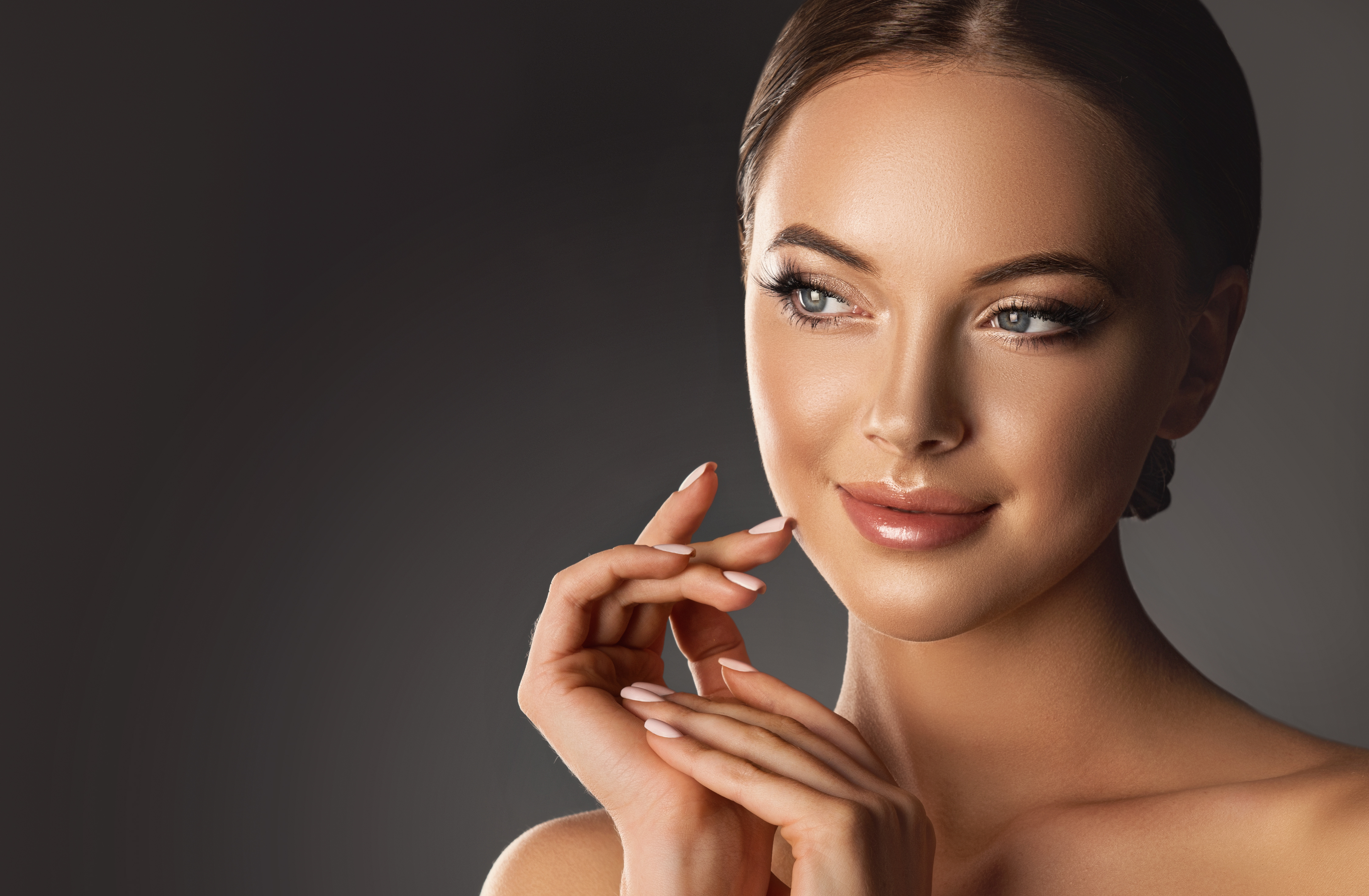Woman with smooth, healthy skin resting her hand near her jawline