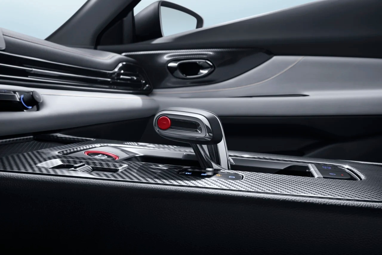 Primer plano del elegante interior de un automóvil con una consola central de fibra de carbono con una moderna palanca de cambios y un botón de arranque.