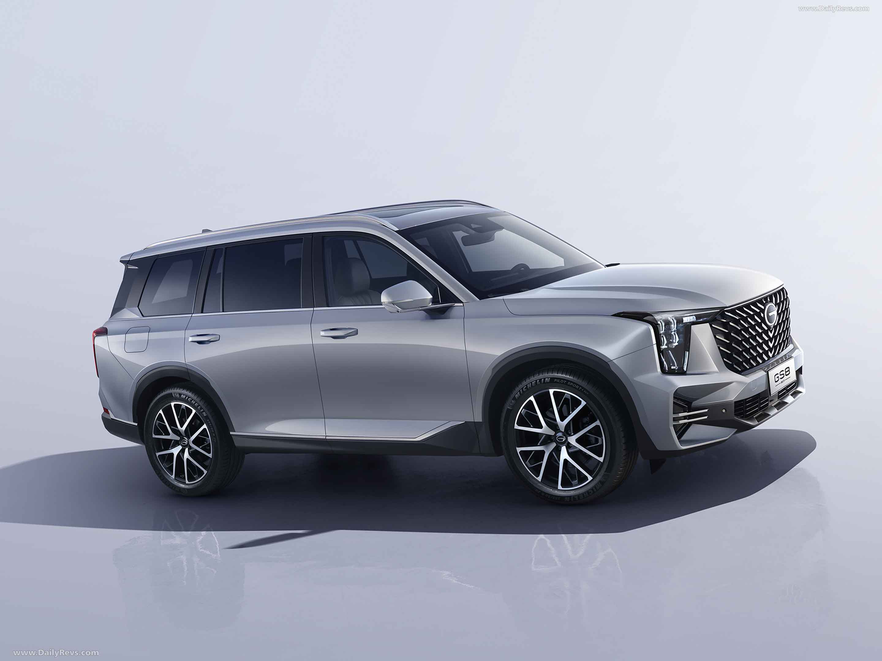SUV GS8 plateado con modernos faros angulares y una gran parrilla negra sobre una superficie reflectante.