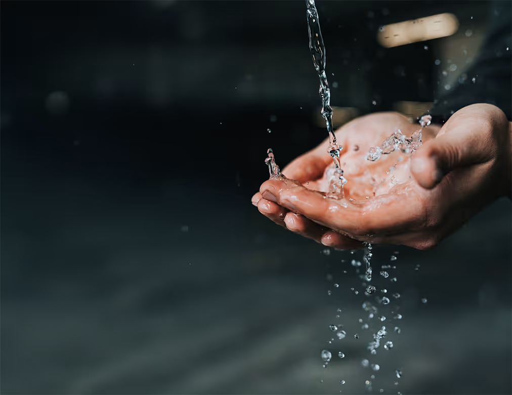 Hände, in die Wasser fließt und heruntertröpfelt