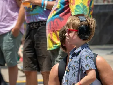 A child wearing earmuffs at a city street fair