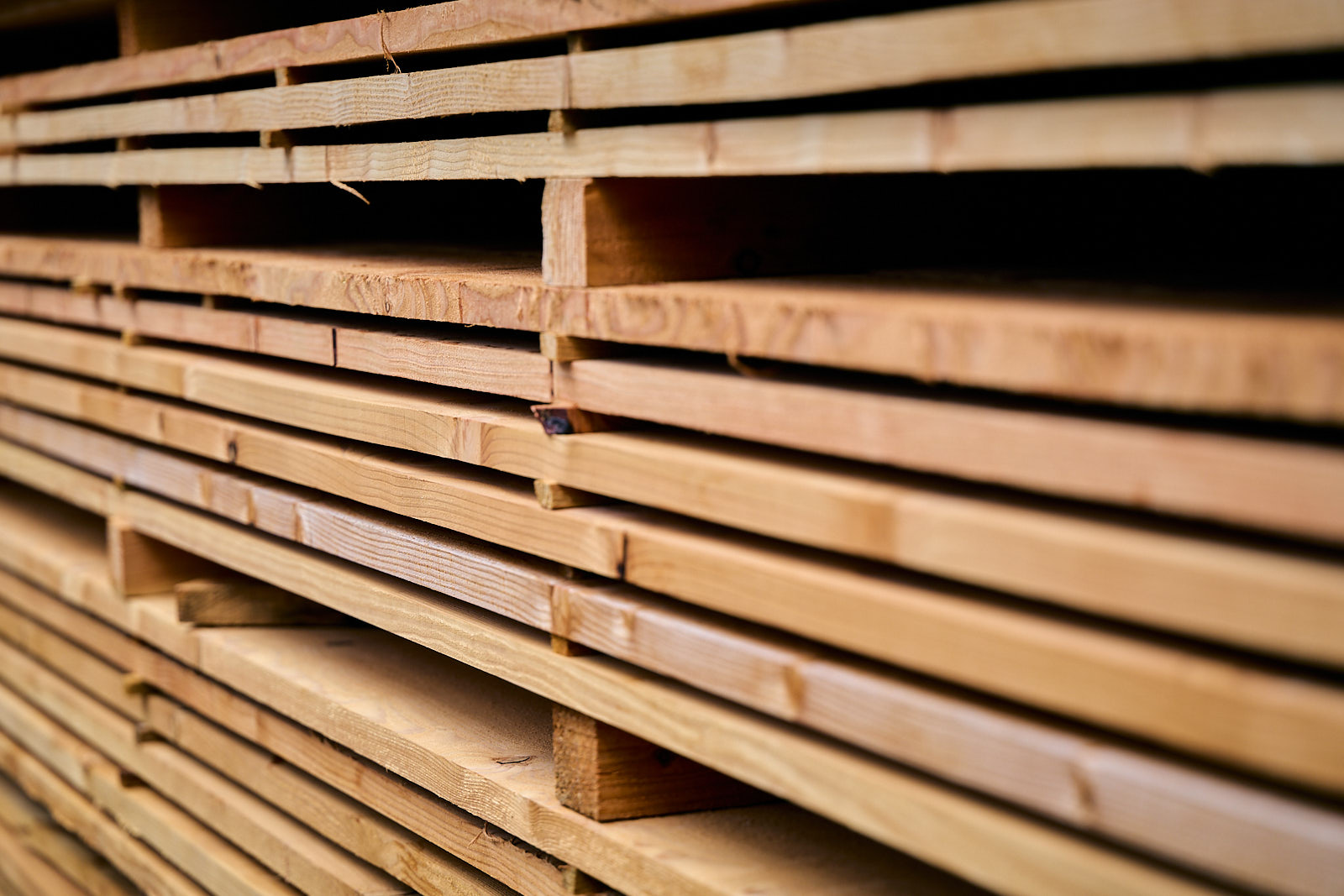 Stack of neatly arranged wooden planks in a lumberyard.
