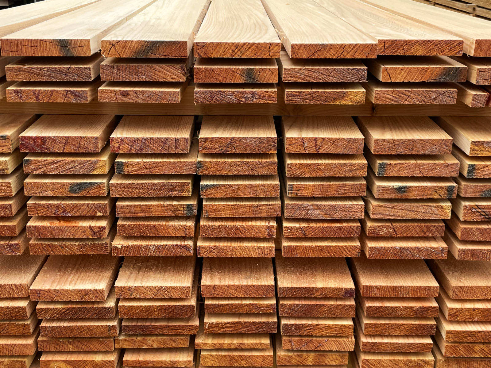 Stack of neatly arranged raw wooden planks with visible grain and texture.