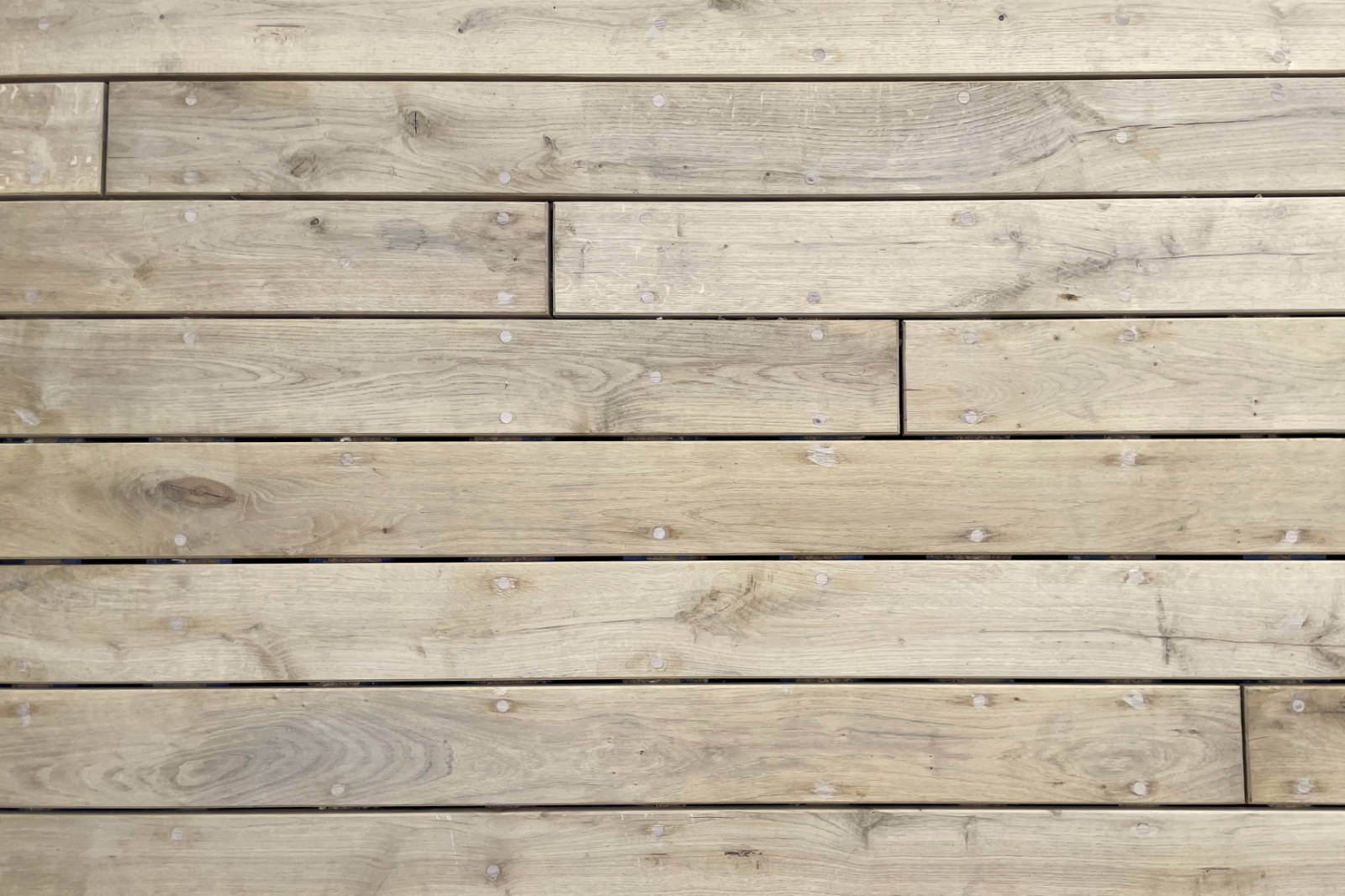 Light-colored wooden floorboards laid horizontally with visible knots and round fasteners.