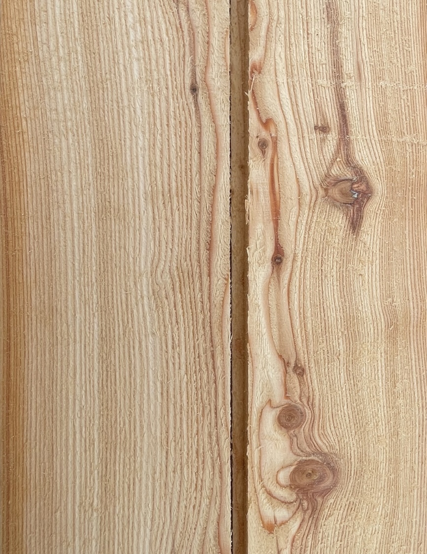 Close-up of two wooden boards with visible growth rings and knots separated by a narrow gap.