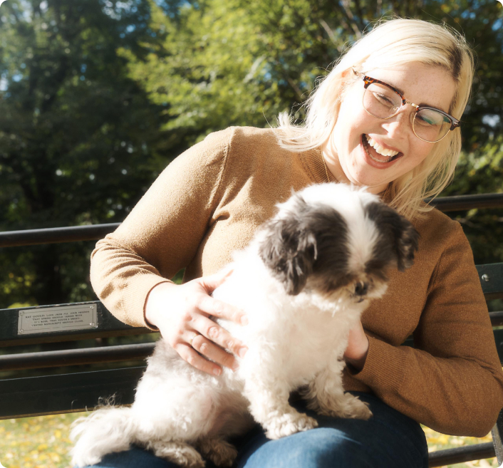 A woman on a bench with her puppy.