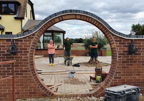 Image of the JG Team standing proudly with the client looking at the construction progress of a brick archway half way through a renovation project.