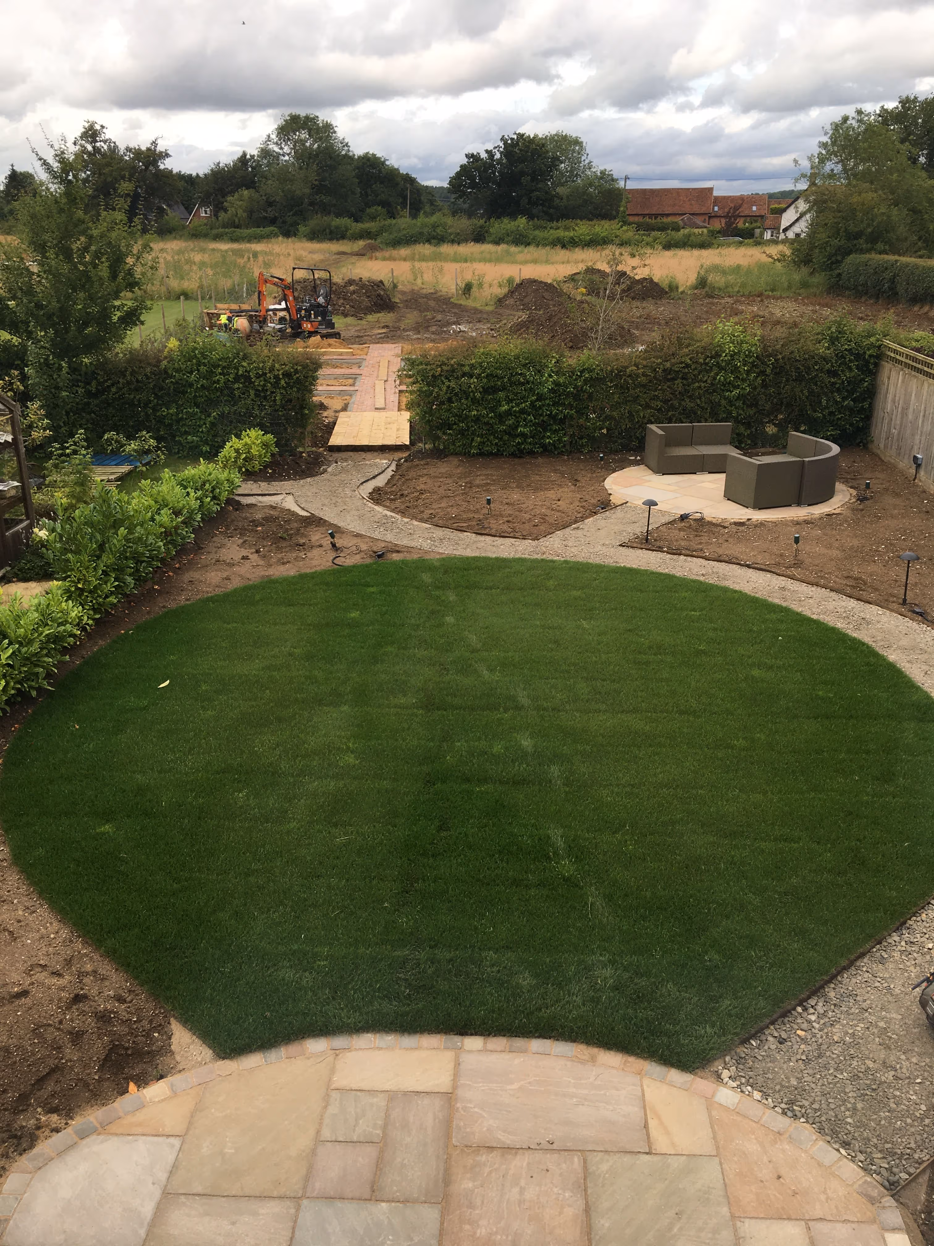 Back garden in the process of getting renovated. new look healthy lawn has been laid with the surrounding area under construction. A new patio curved patio area has also been laid at the front of the lawn and another circular paved area at the rear of the garden with new outdoor furniture.