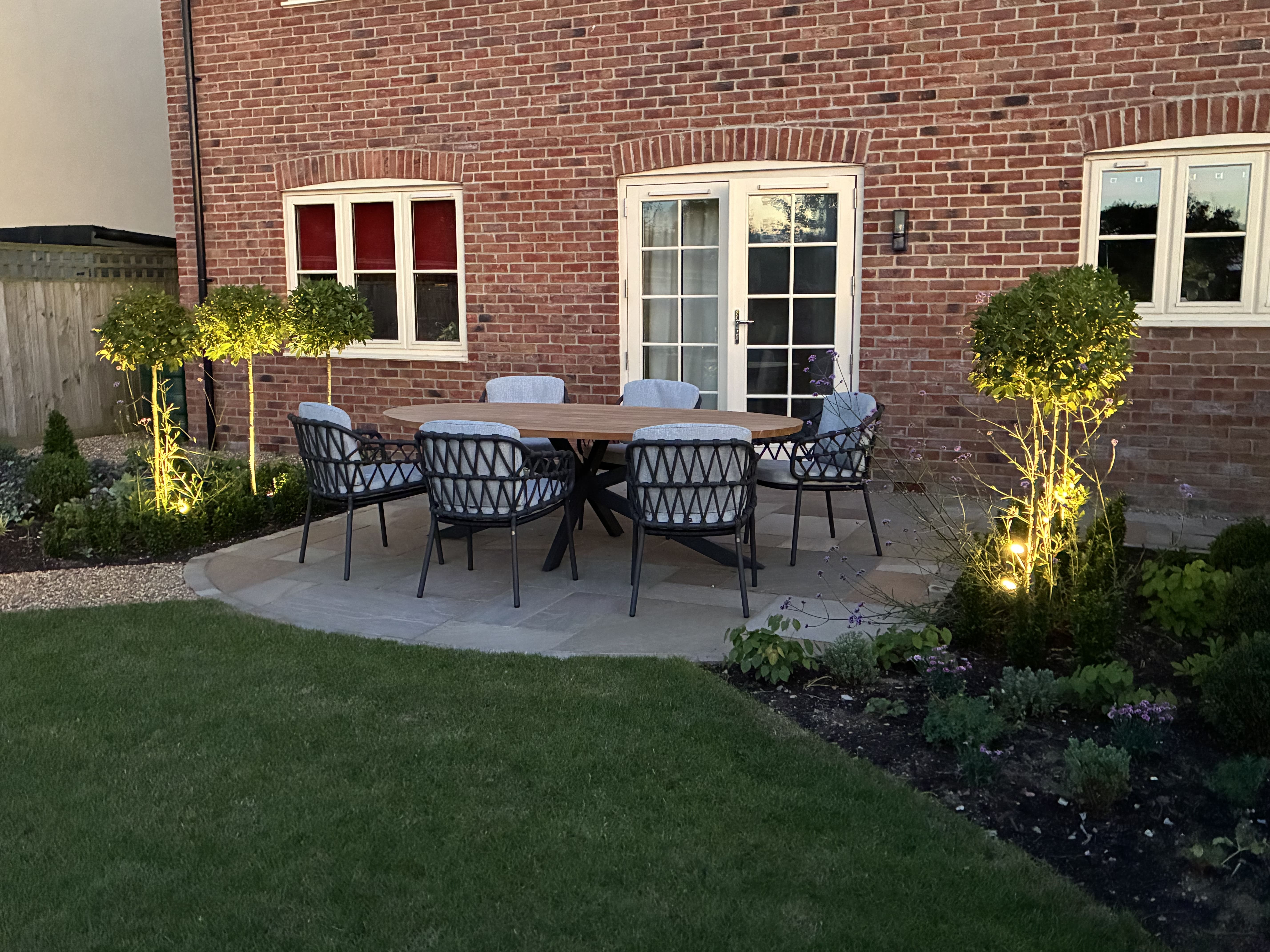 Outdoor dining area with lit dwarf trees either side of the dining area creating a very relaxed secluded atmosphere.