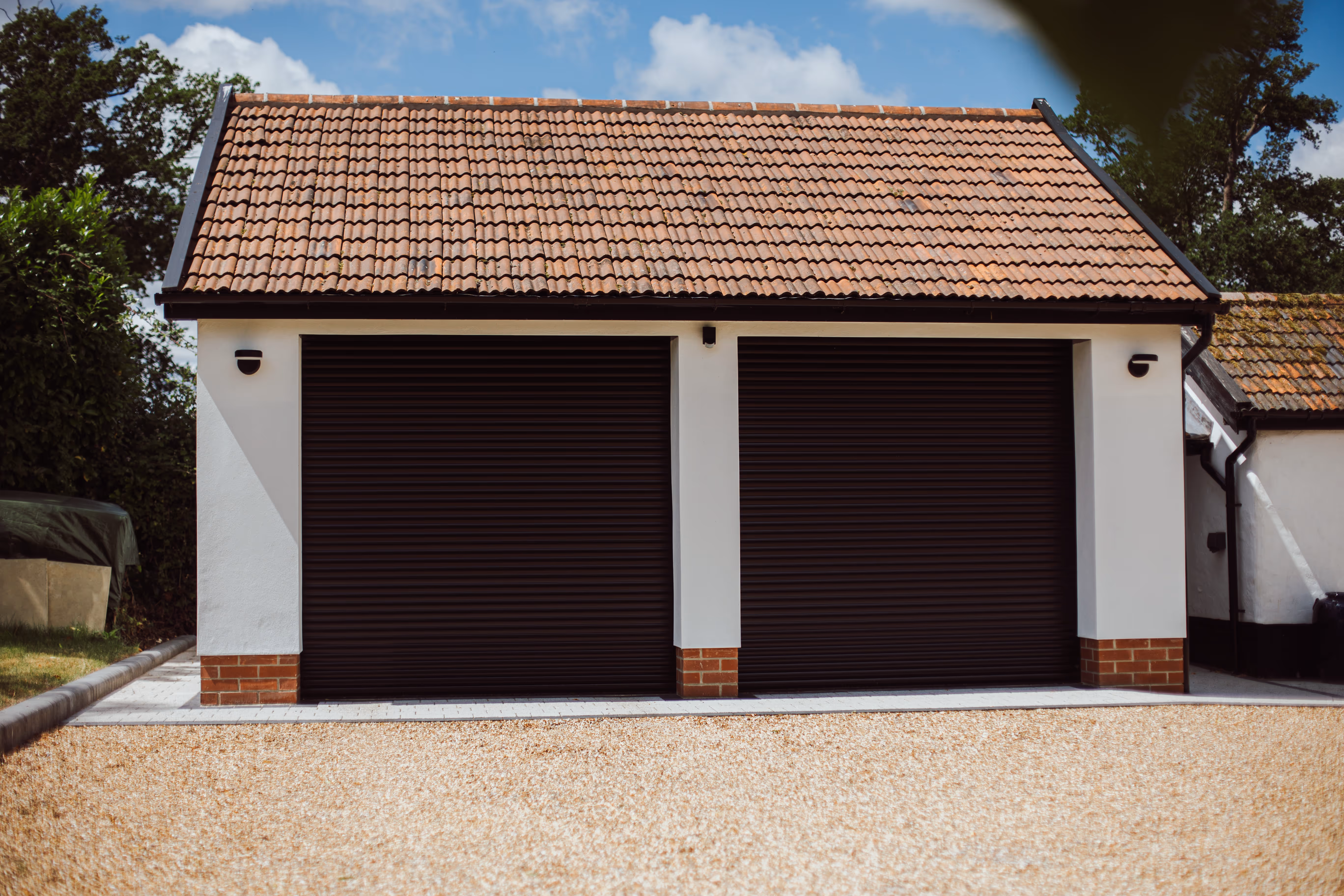Front view of a double garage, white rendered walls with discreet lighting.
