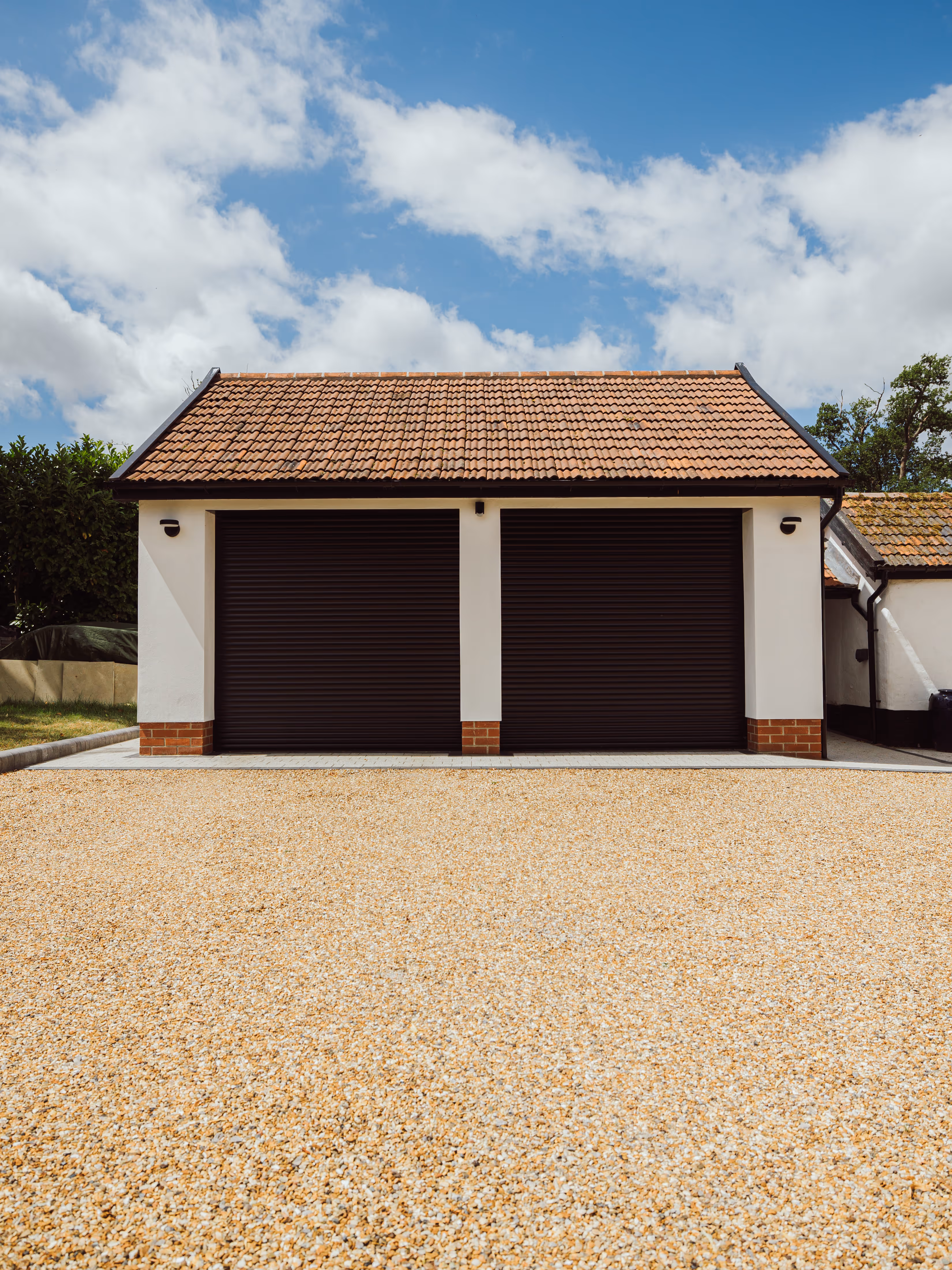Zoomed out view of Double garage doors as well as gravel driveway. 