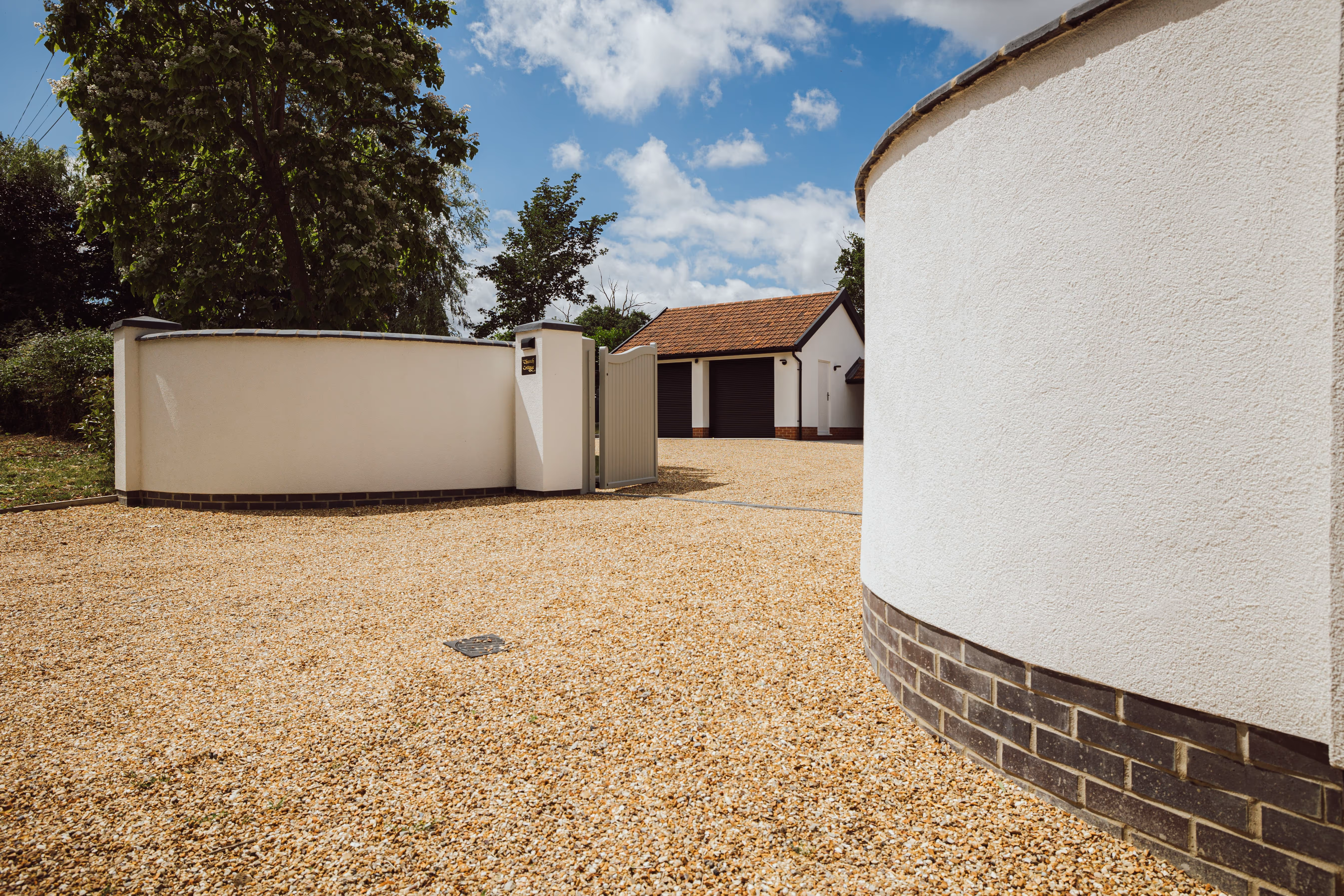 White rendered walls leading onto the gravel driveway at the Church Cottage entrance.