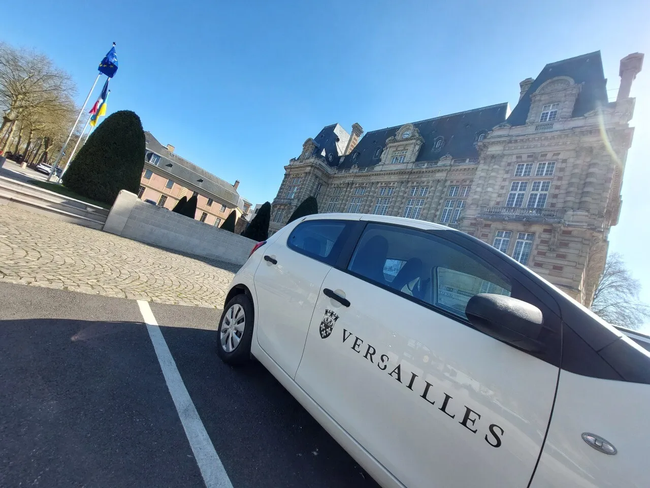 Voiture blanche stationnée devant l'hôtel de ville de Versailles.