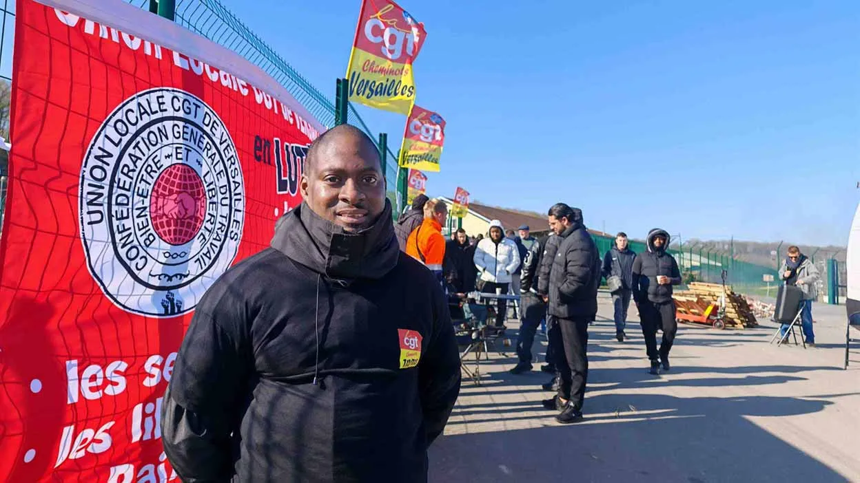 Membre de la CGT en manifestation devant un drapeau rouge.