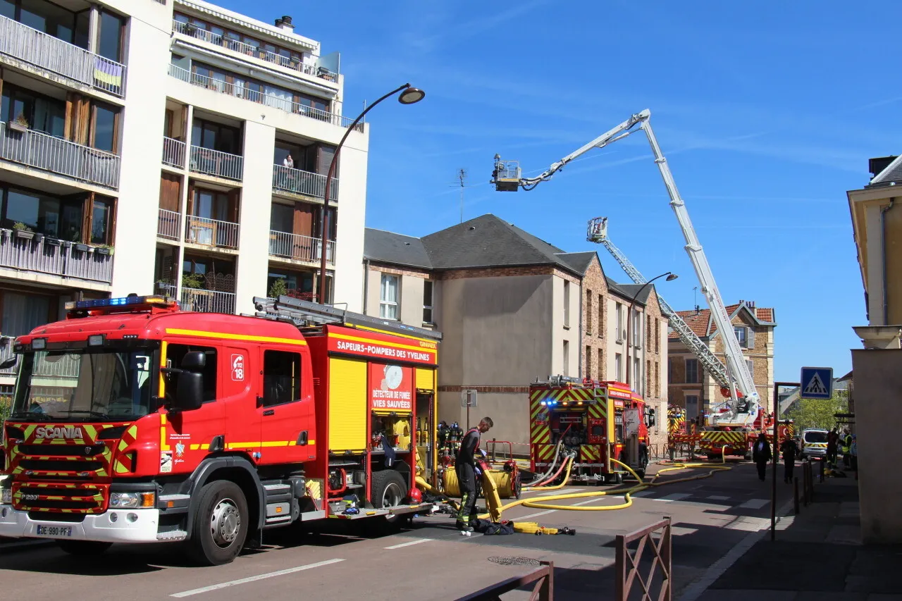 Intervention des pompiers avec véhicules et échelle en ville.