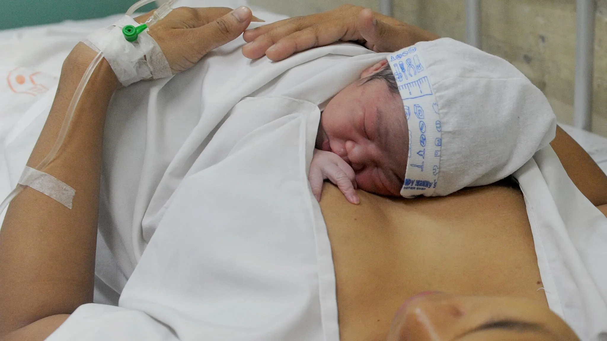Bébé nouveau-né enveloppé dans une couverture, reposant sur la poitrine de sa mère.