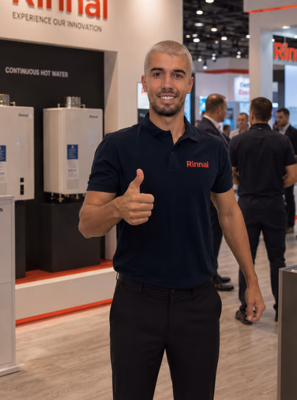Man in black Rinnai polo shirt giving thumbs up at a booth with continuous hot water systems.