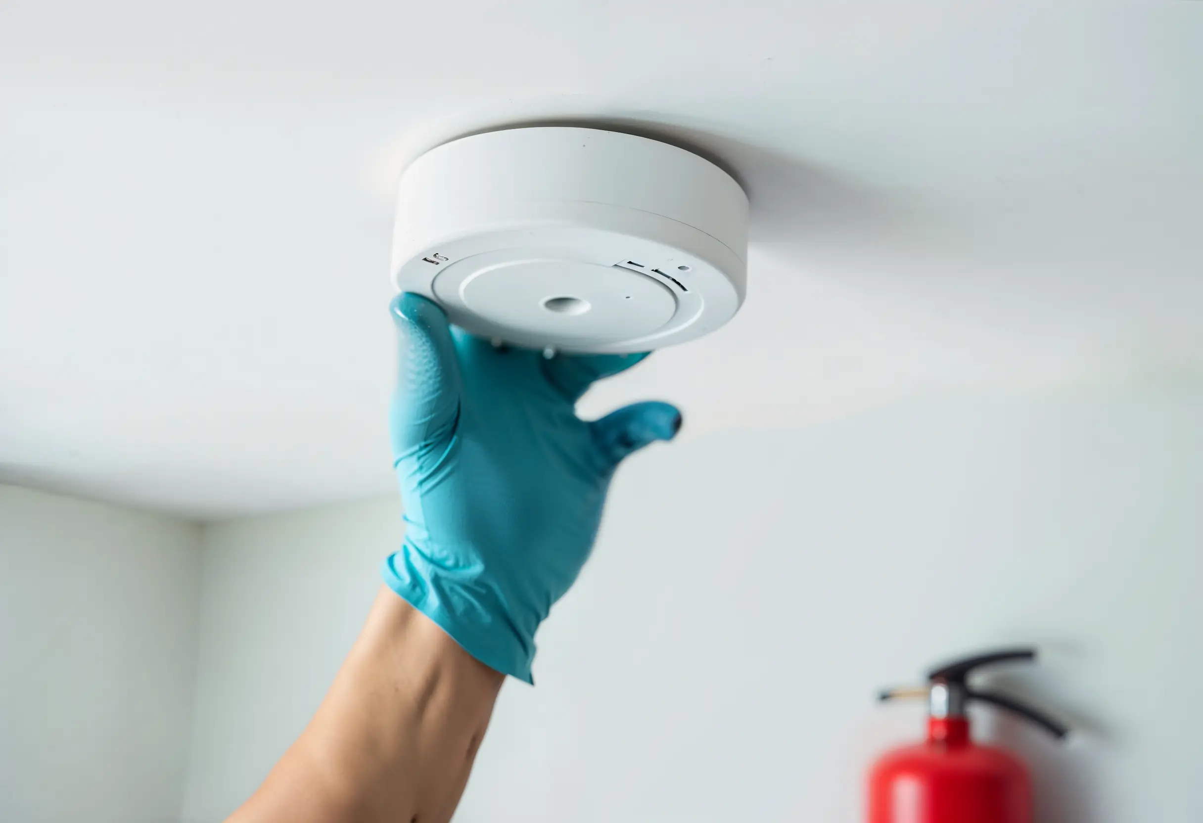 Technician installing a smoke detector as part of home fire safety setup.