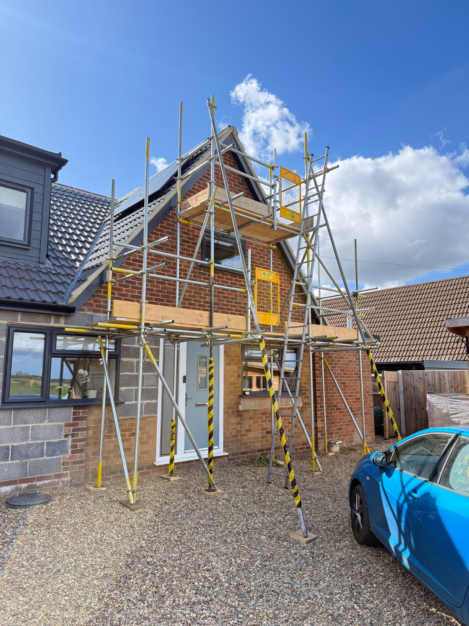 Worker standing on platform of scaffolding.