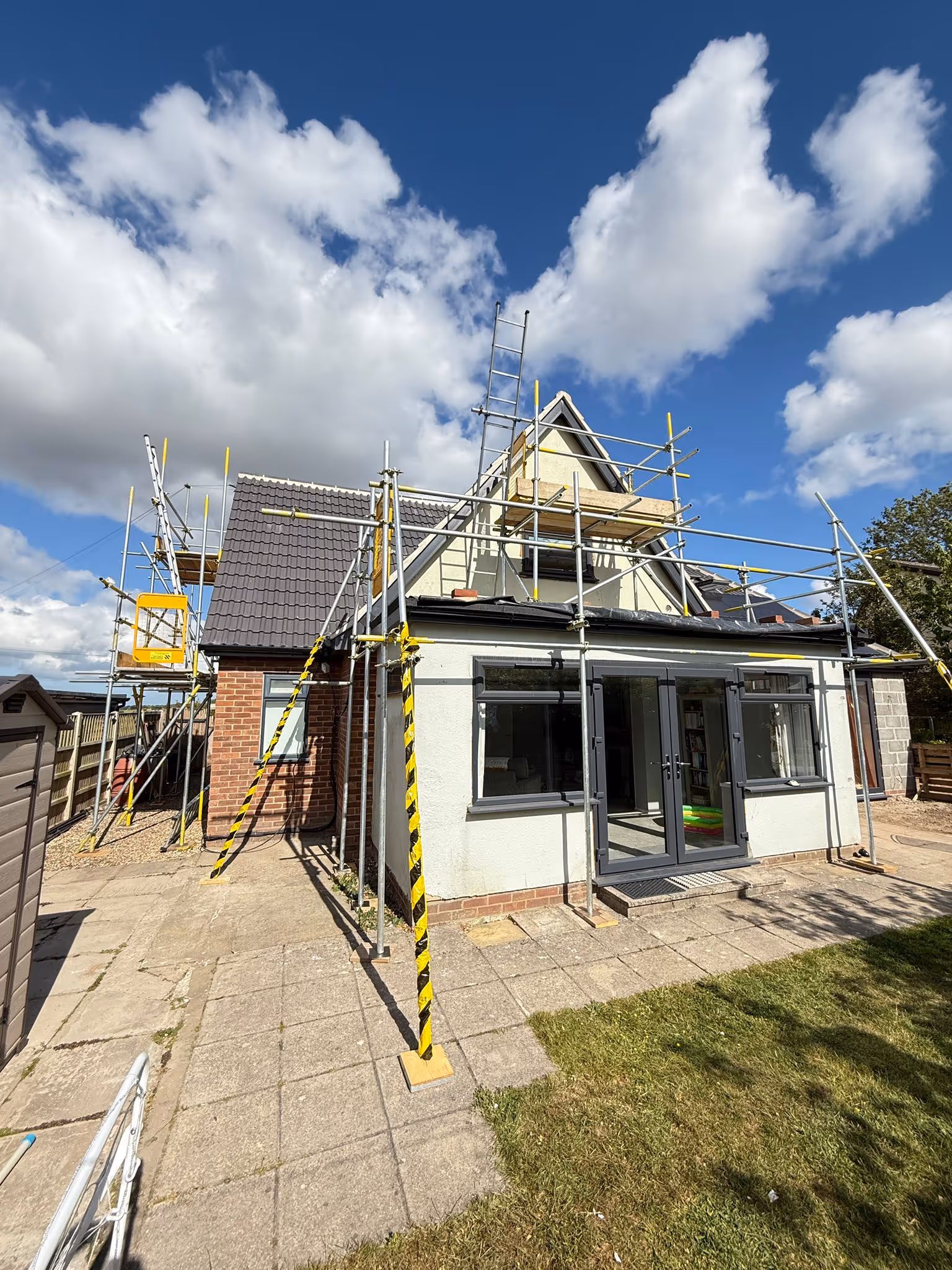 Scaffolding along back of house with plenty of safety hazard tape.