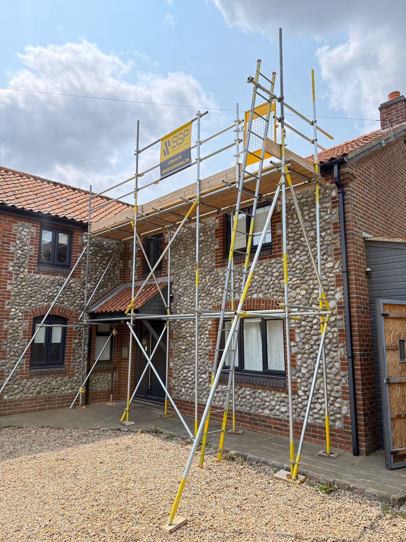 Scaffolding along the front of flint stone house and SSP banner clearly displayed on top poles of the scaffolding.