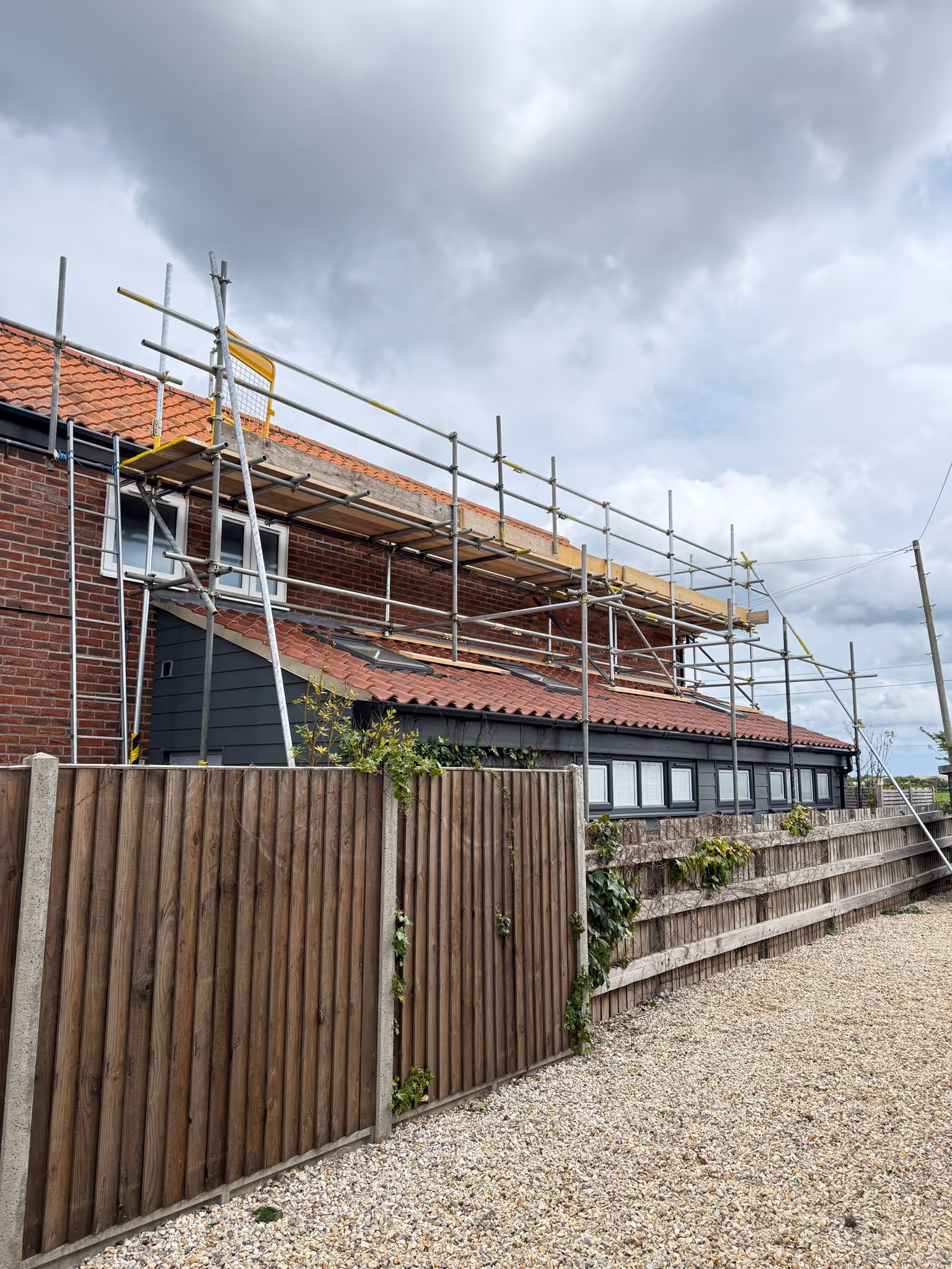 Worker standing on platform of scaffolding.