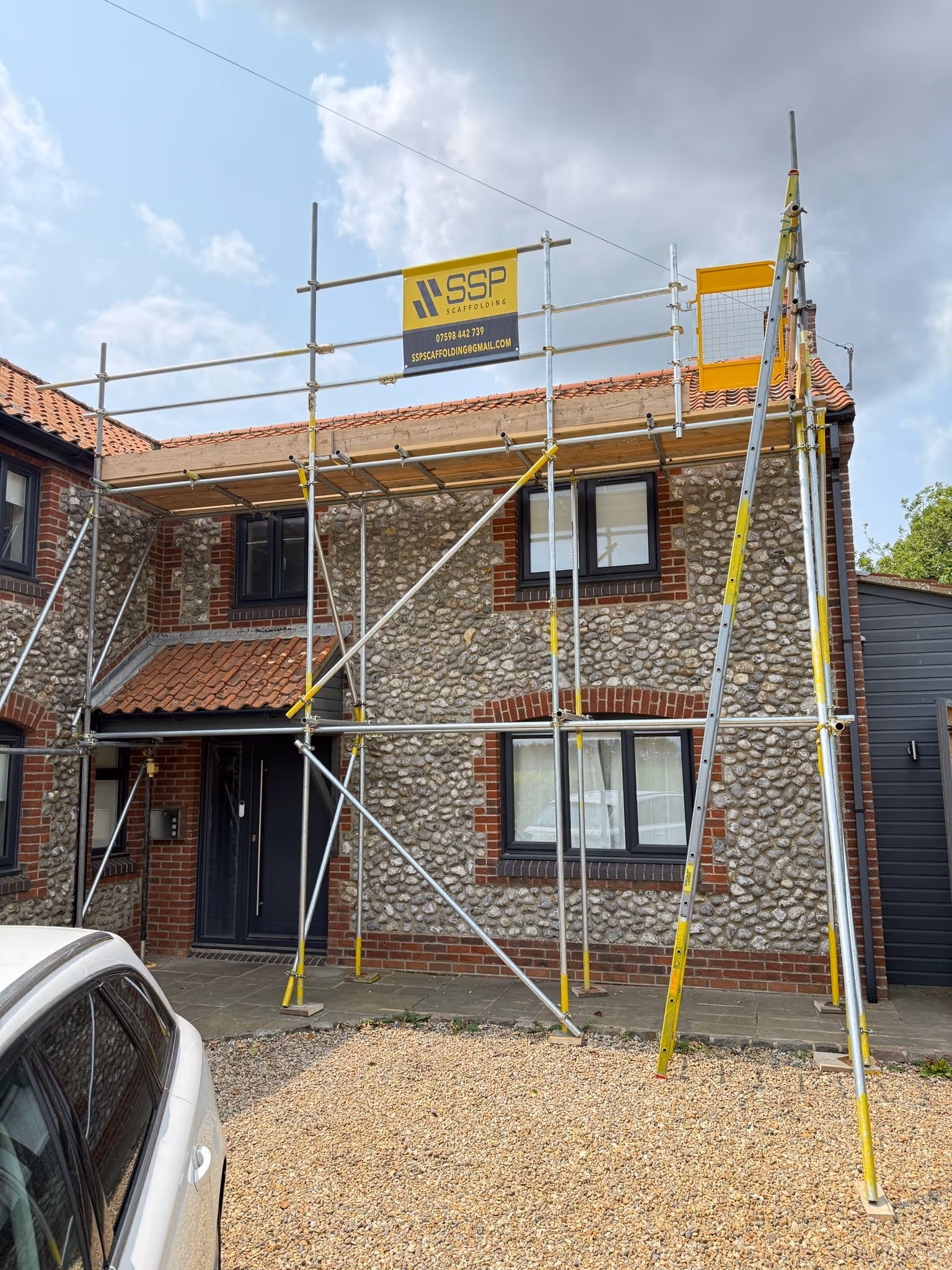 Scaffolding along the front of flint stone house and SSP banner clearly displayed on top poles of the scaffolding.