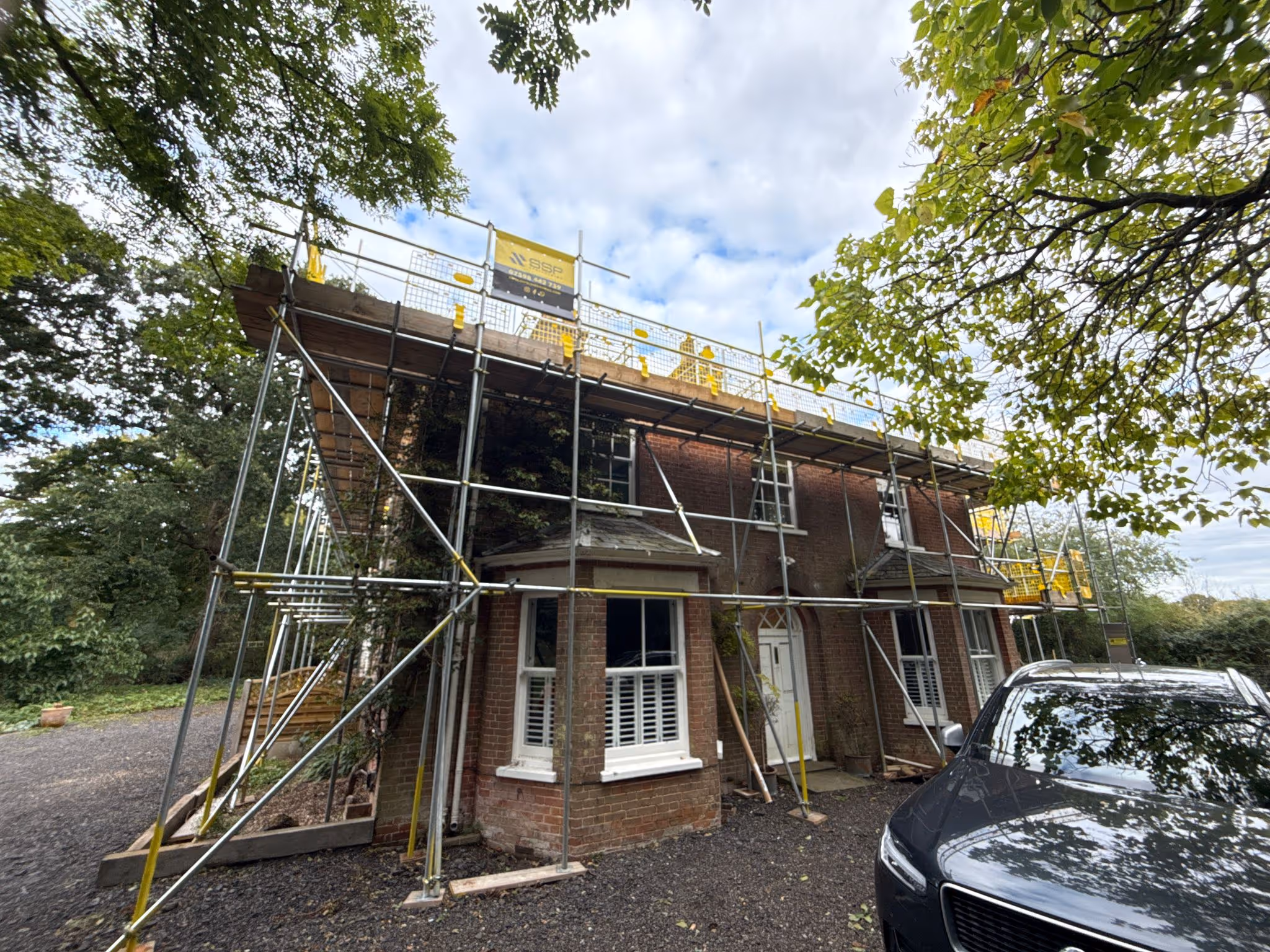 Scaffolding built along the front of brick house and SSP banner showcased on top level.