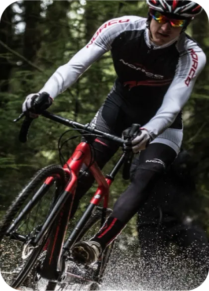 A cyclist riding a red bike through a forest trail