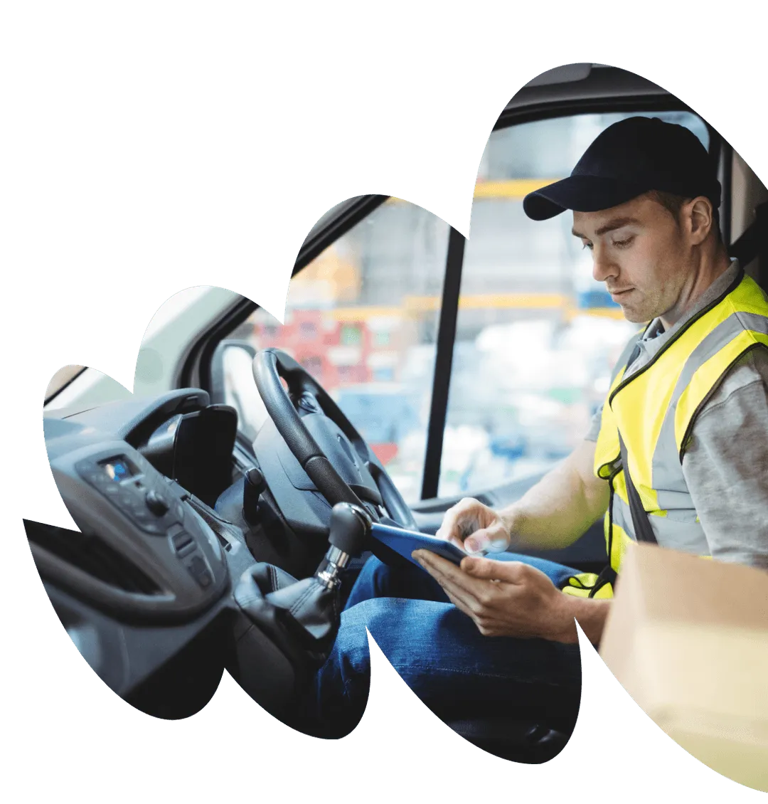 Delivery driver sitting in van, typing on tablet