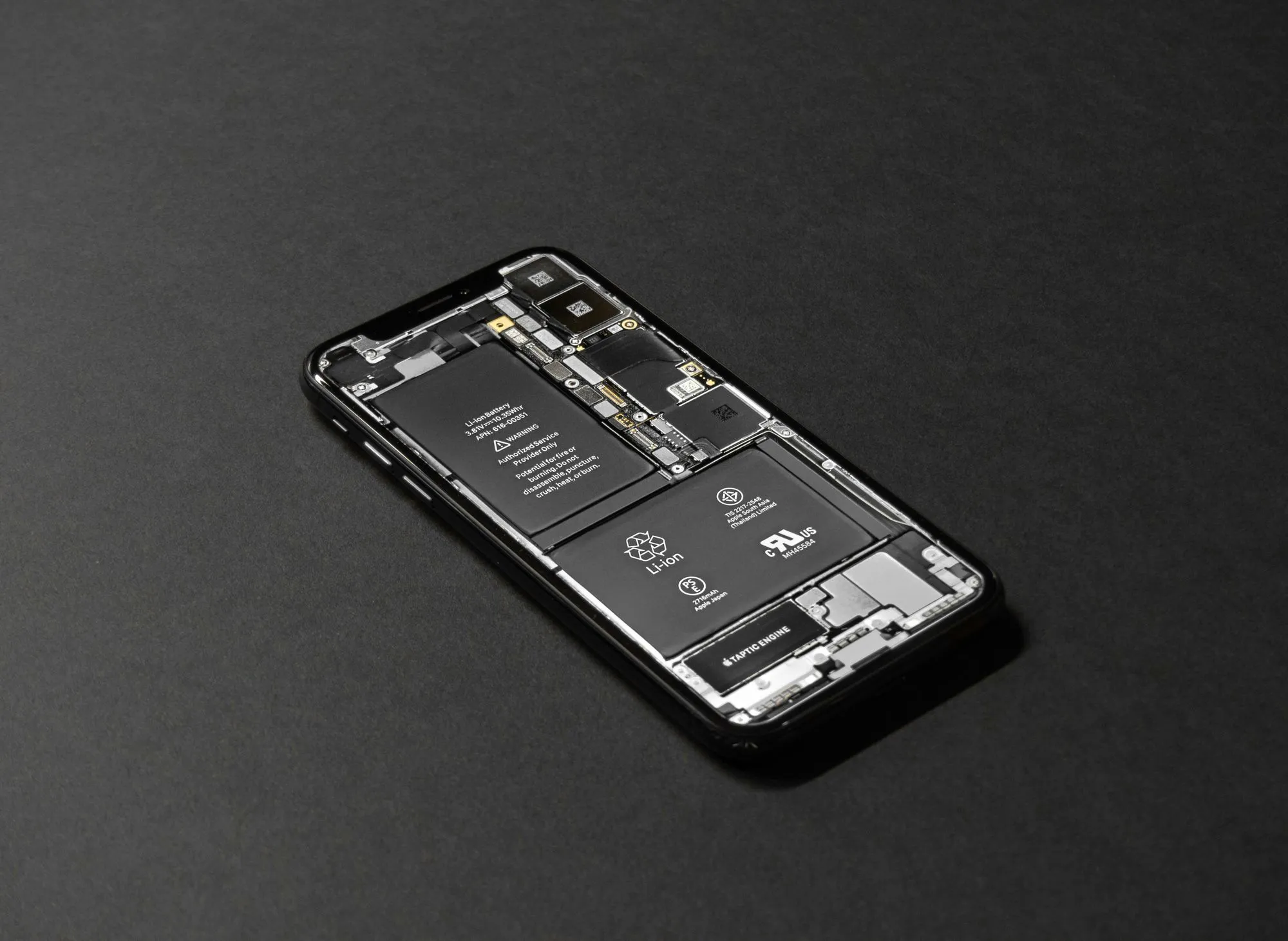 A smartphone with its back cover removed, revealing the internal components such as the lithium-ion battery and other hardware parts