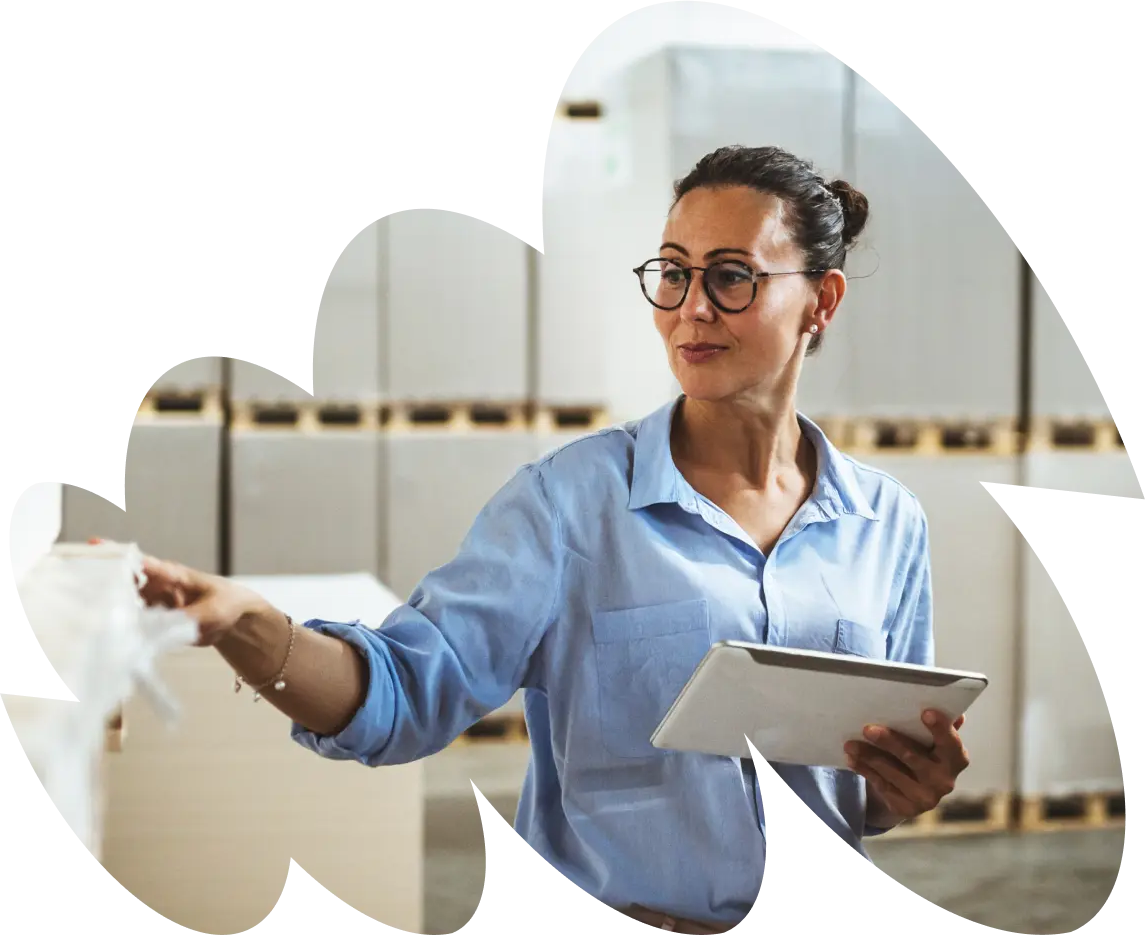 A woman in a warehouse holding a tablet, pointing to something out of view