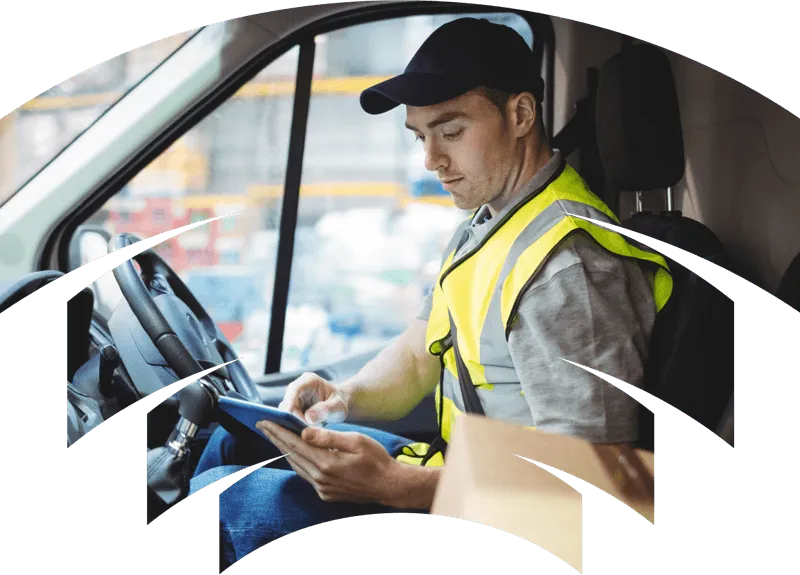 Delivery driver sitting in van, typing on tablet