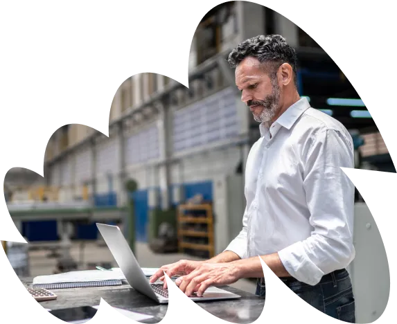 Man standing in warehouse typing on computer