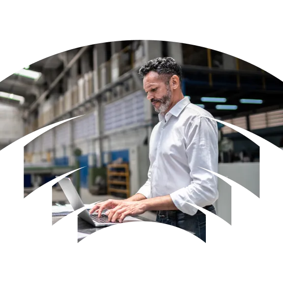 A man working on a laptop in a factory.