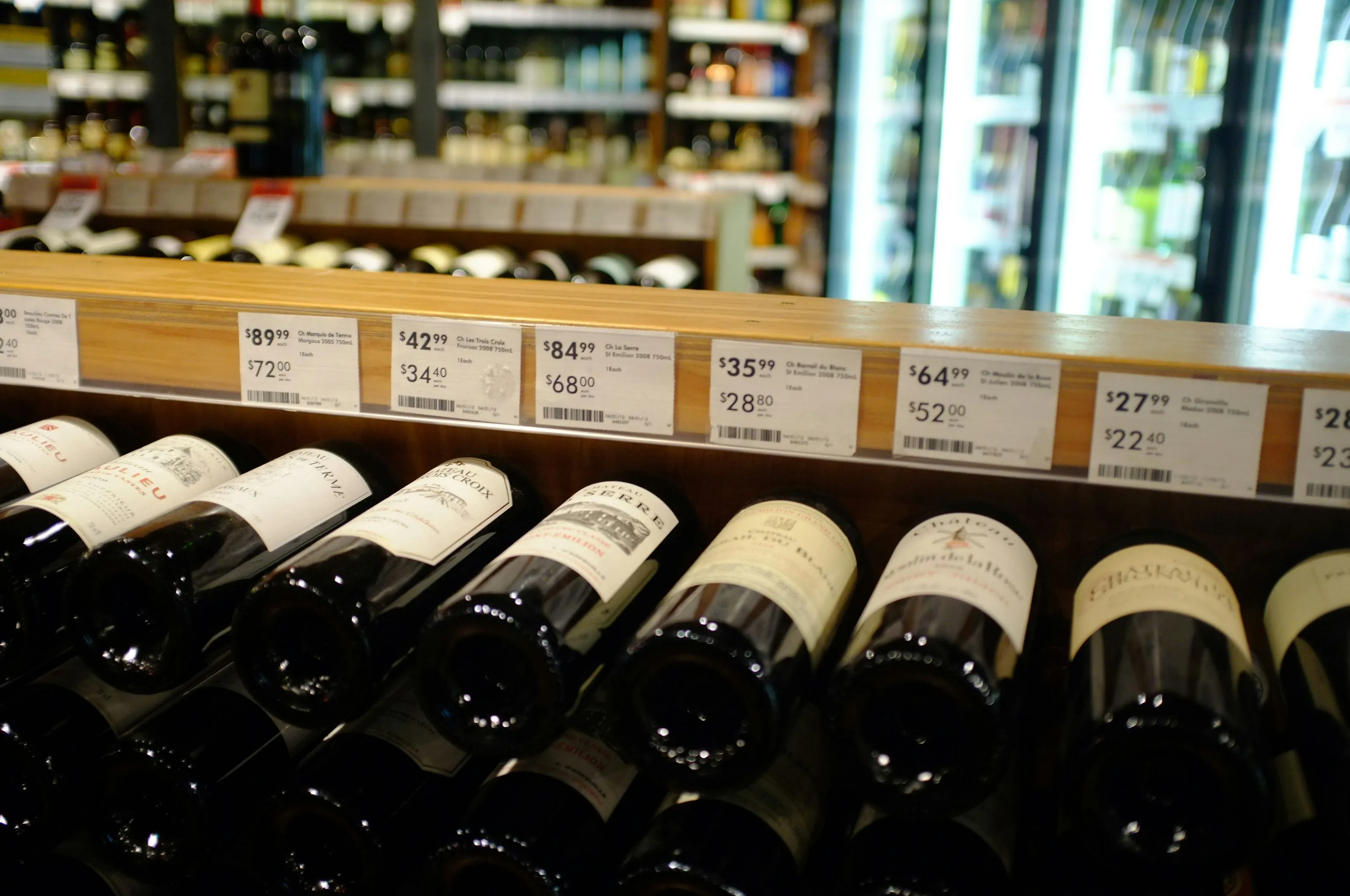 Bottles of wine are lined up on a shelf.