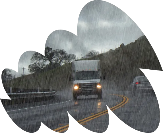 A truck driving down a rain soaked road.