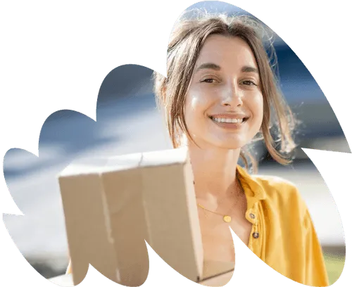 A woman holding a cardboard box and smiling.