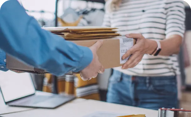 Customer receiving a package and envelopes from a delivery person in an office setting