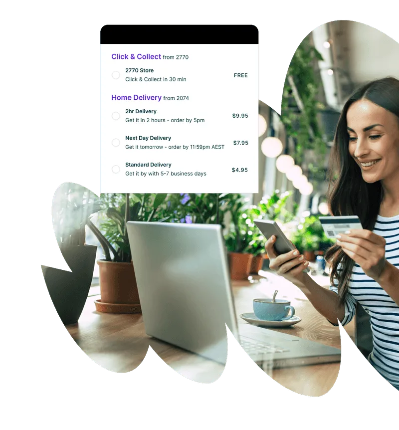 Smiling woman sitting at a table with a laptop, holding a credit card and phone, reviewing delivery options for Click & Collect and Home Delivery services