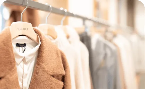 Clothing rack displaying neatly hung garments, including a brown coat on a hanger