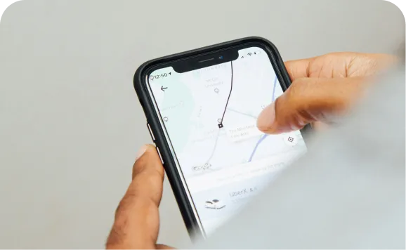 A person using a smartphone to track a location on a map, showing a route with a pin marker.