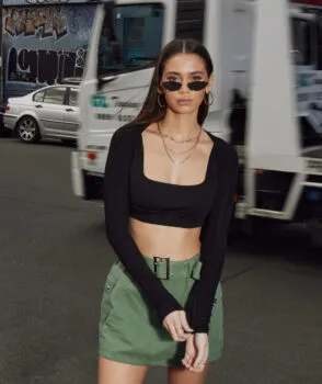 Girl wearing sunglasses, black top and green shorts