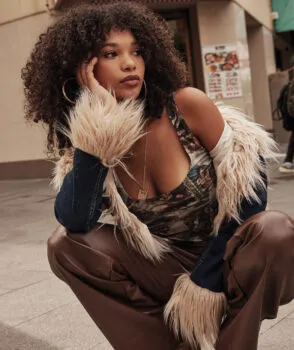 Woman crouching down weaing brown pants and fluffy coat