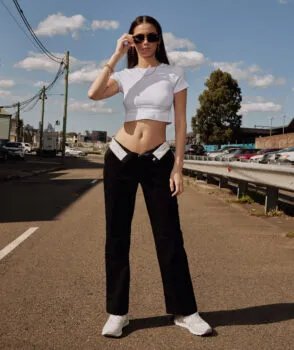 Woman wearing white crop top and black pants standing on road