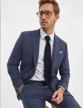 Man seated wearing a suit and glasses