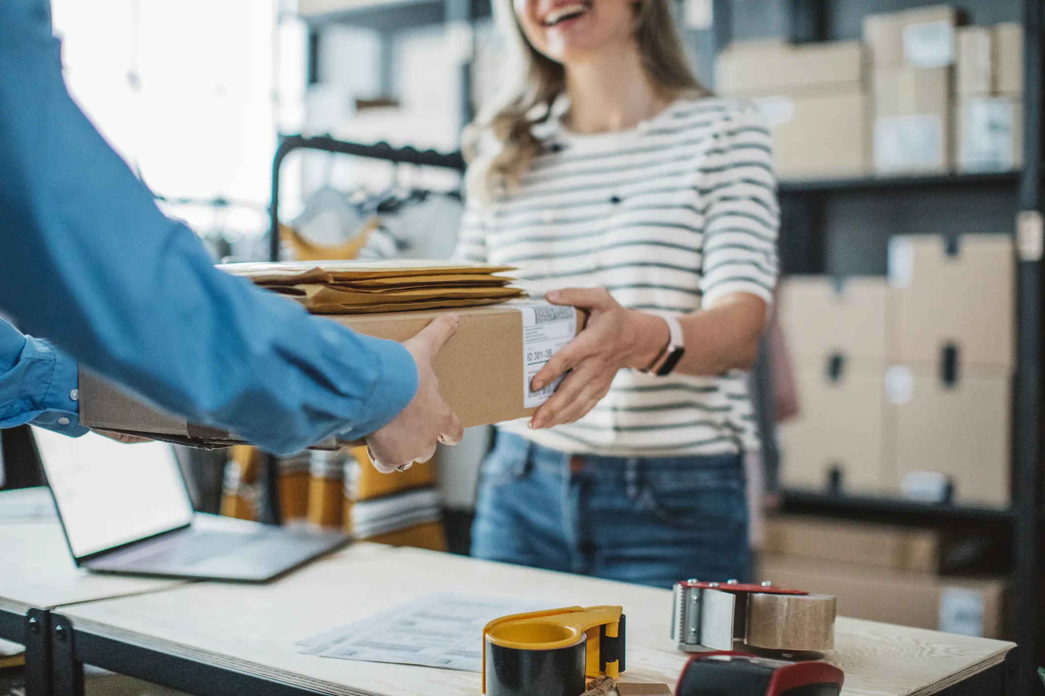A retailer handing a box across a counter to a customer